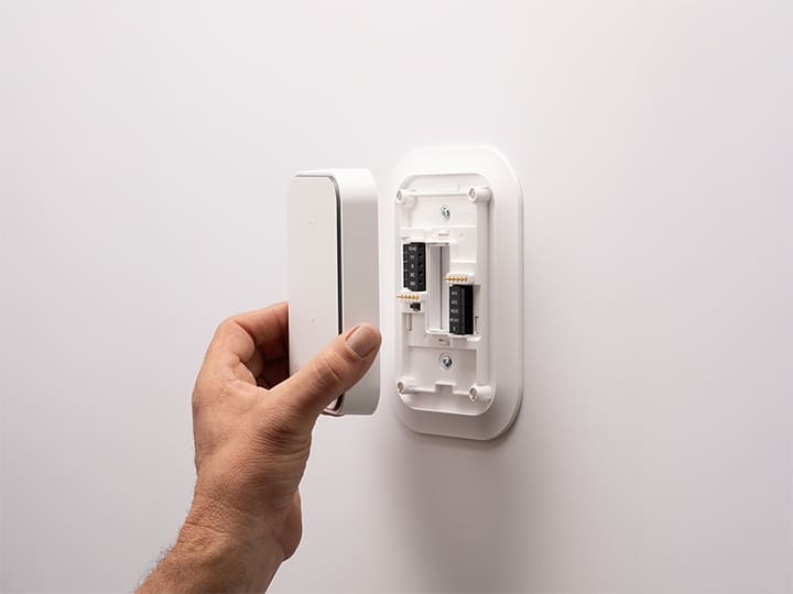Man’s hand attaching the Carrier smart thermostat to the wall