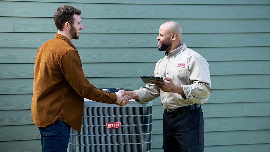 homeowner shakes hands with bryant dealer after central air conditioner installation