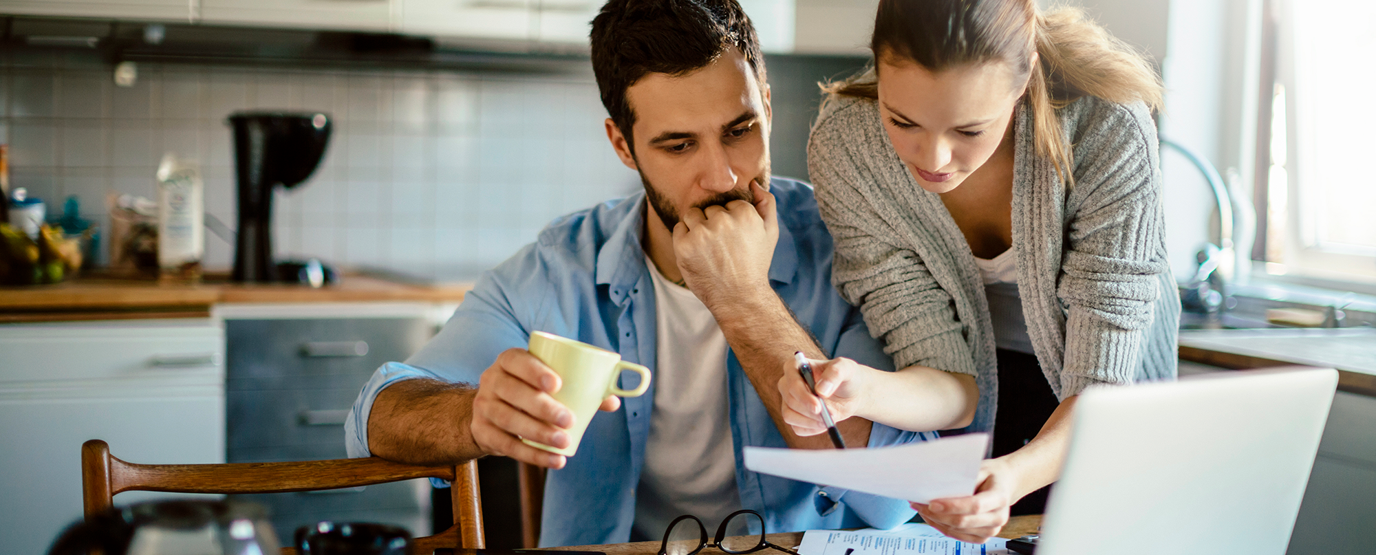 couple-at-kitchen-table-with-coffee-reviewing-finances couple-at-kitchen-table-with-coffee-reviewing-finances