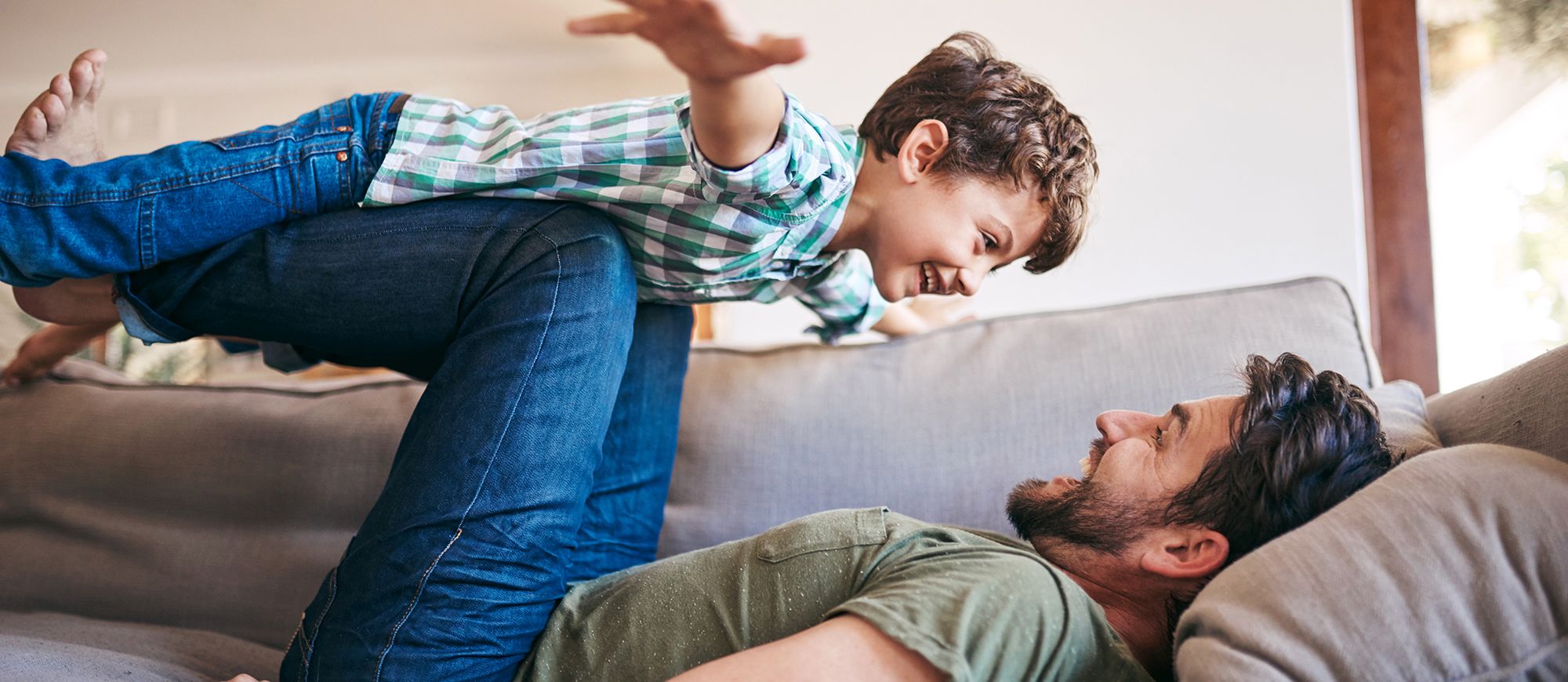 father-and-son-on-couch-playful-cropped father-and-son-on-couch-playful-cropped