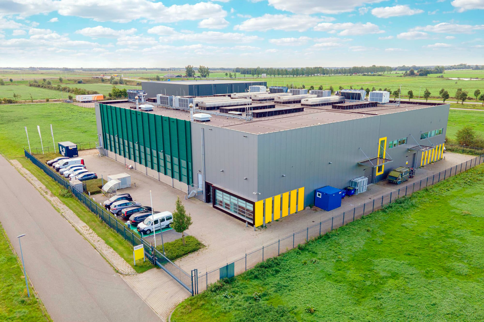 A photo of a data center building in the midlle of green fields in The Netherlands A photo of a data center building in the midlle of green fields in The Netherlands