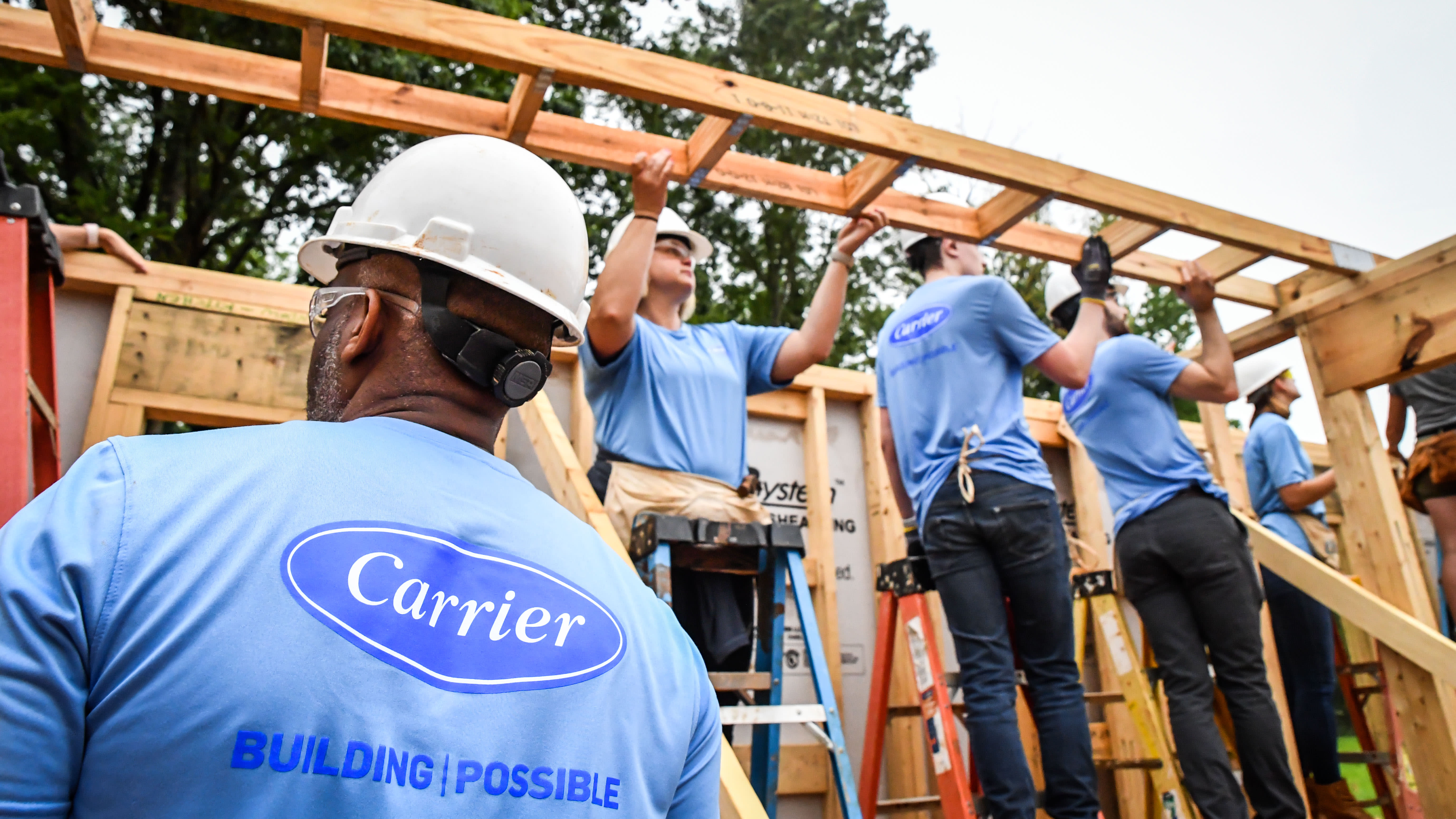 Construction workers wearing t-shirts with the Carrier logo while working on a building site Construction workers wearing t-shirts with the Carrier logo while working on a building site