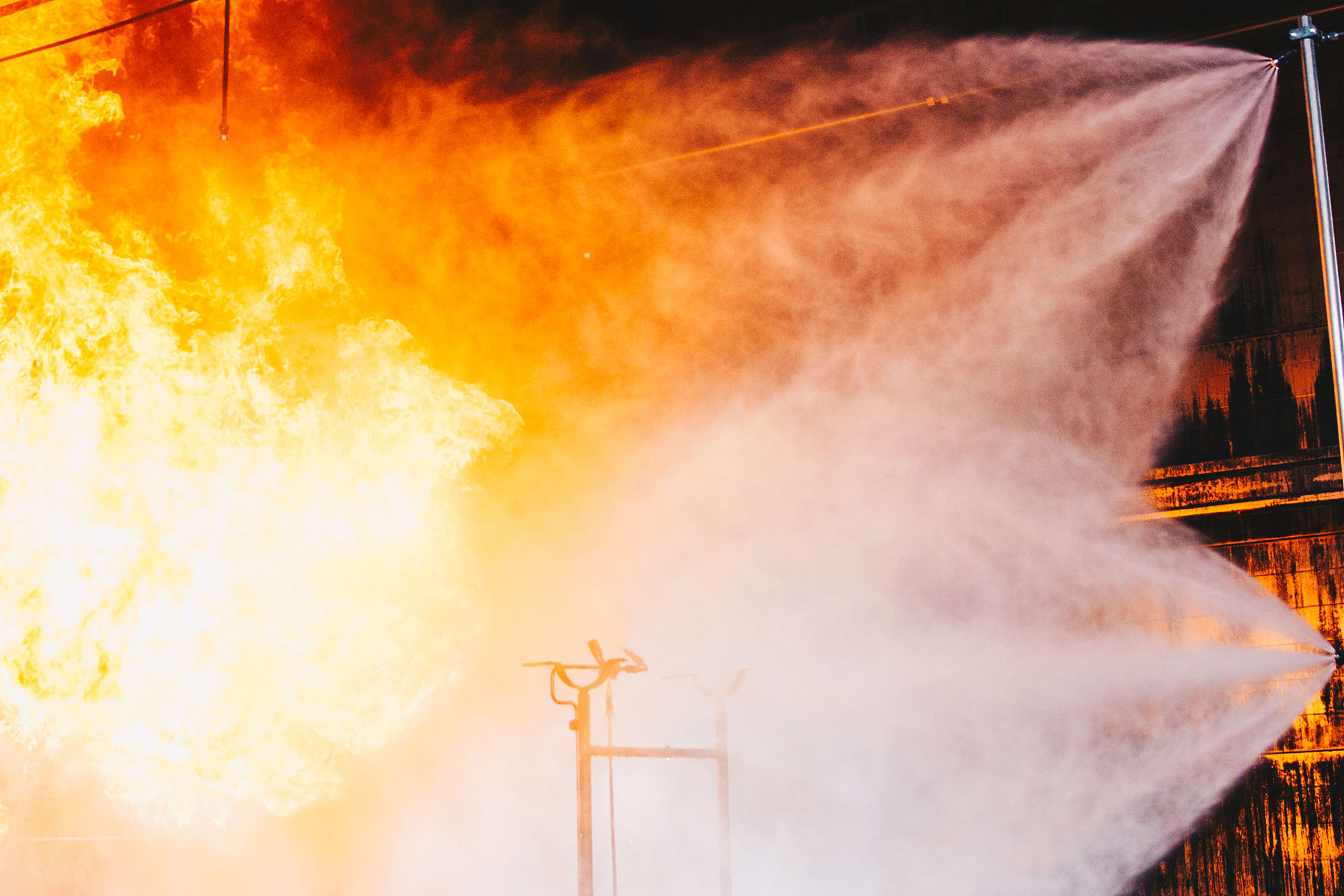 Marioff water mist discharge fights a fire during a local application fire test for land.