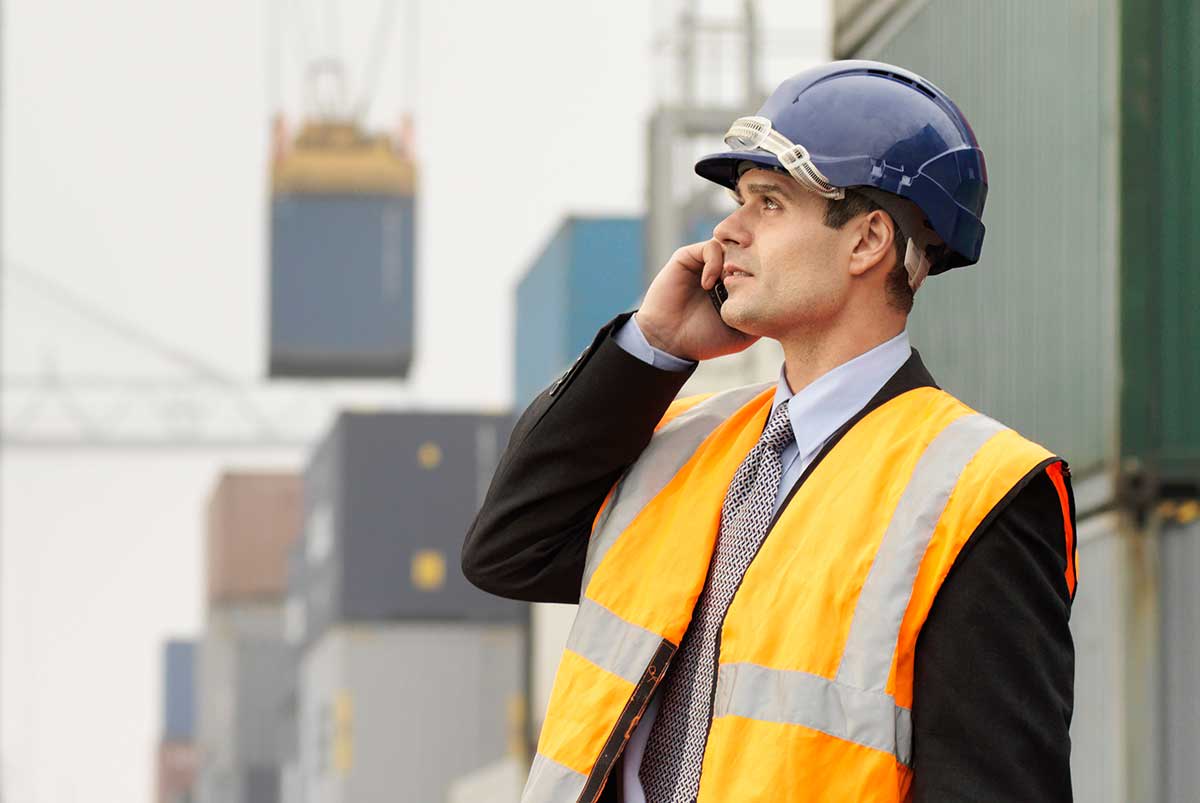 man-hardhat-vest-phone-shipyard