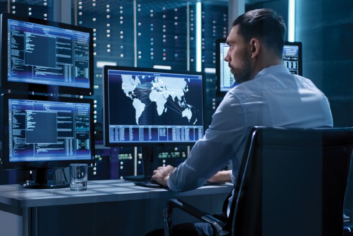 man-viewing-multiple-computer-screens-blue