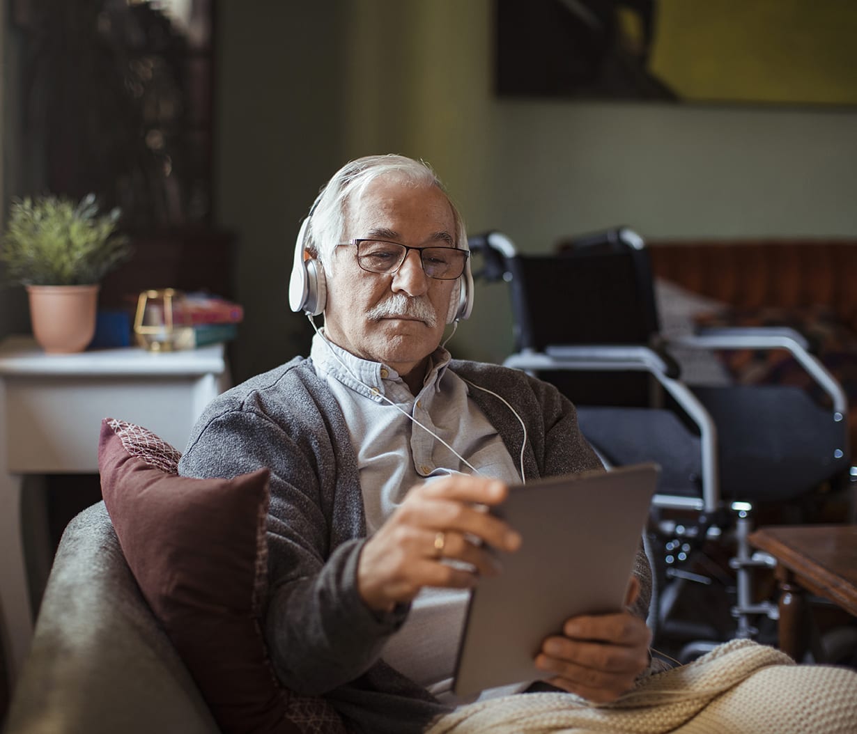 seated-man-with-headphones-and-tablet-and-wheelchair