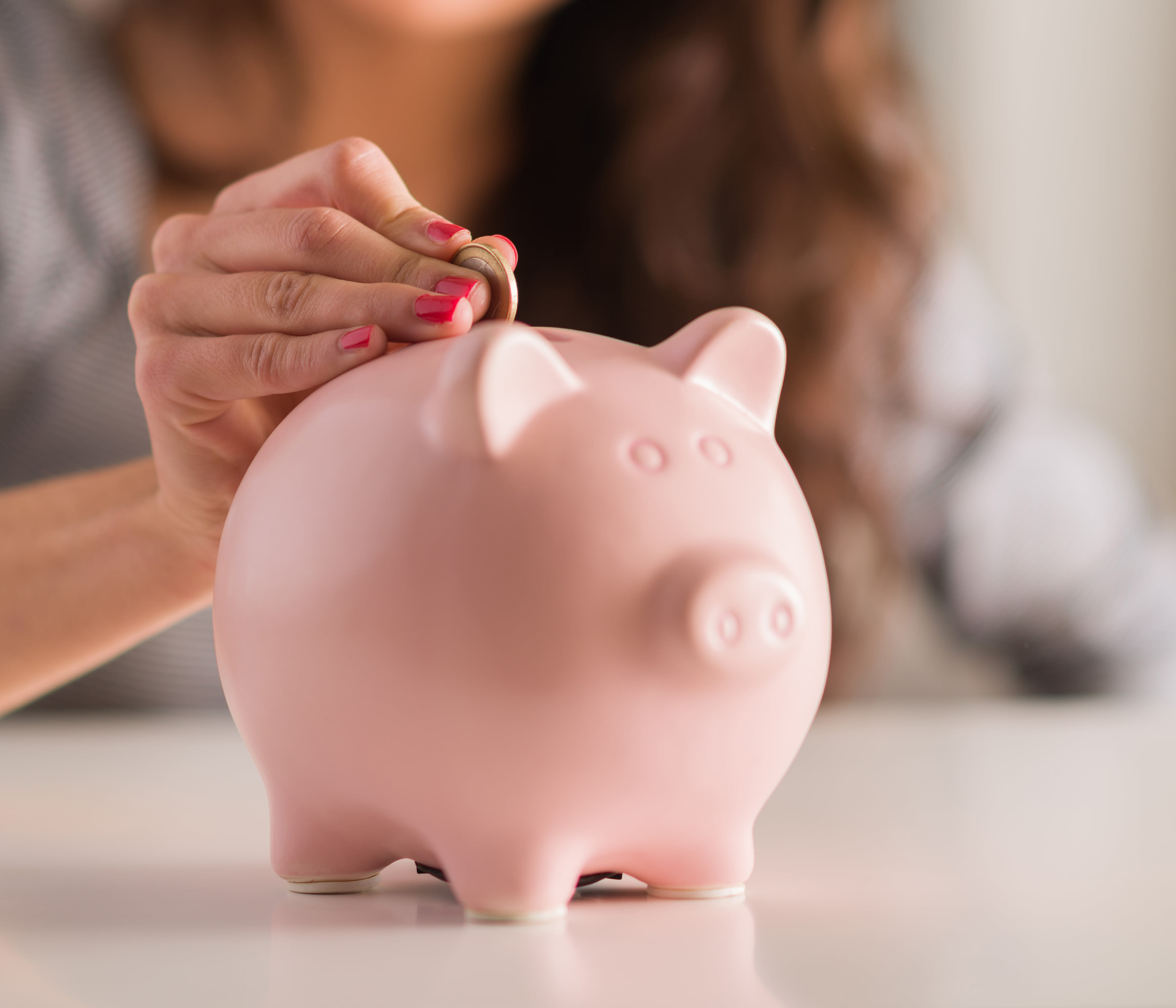 a woman puts a coin in a piggybank