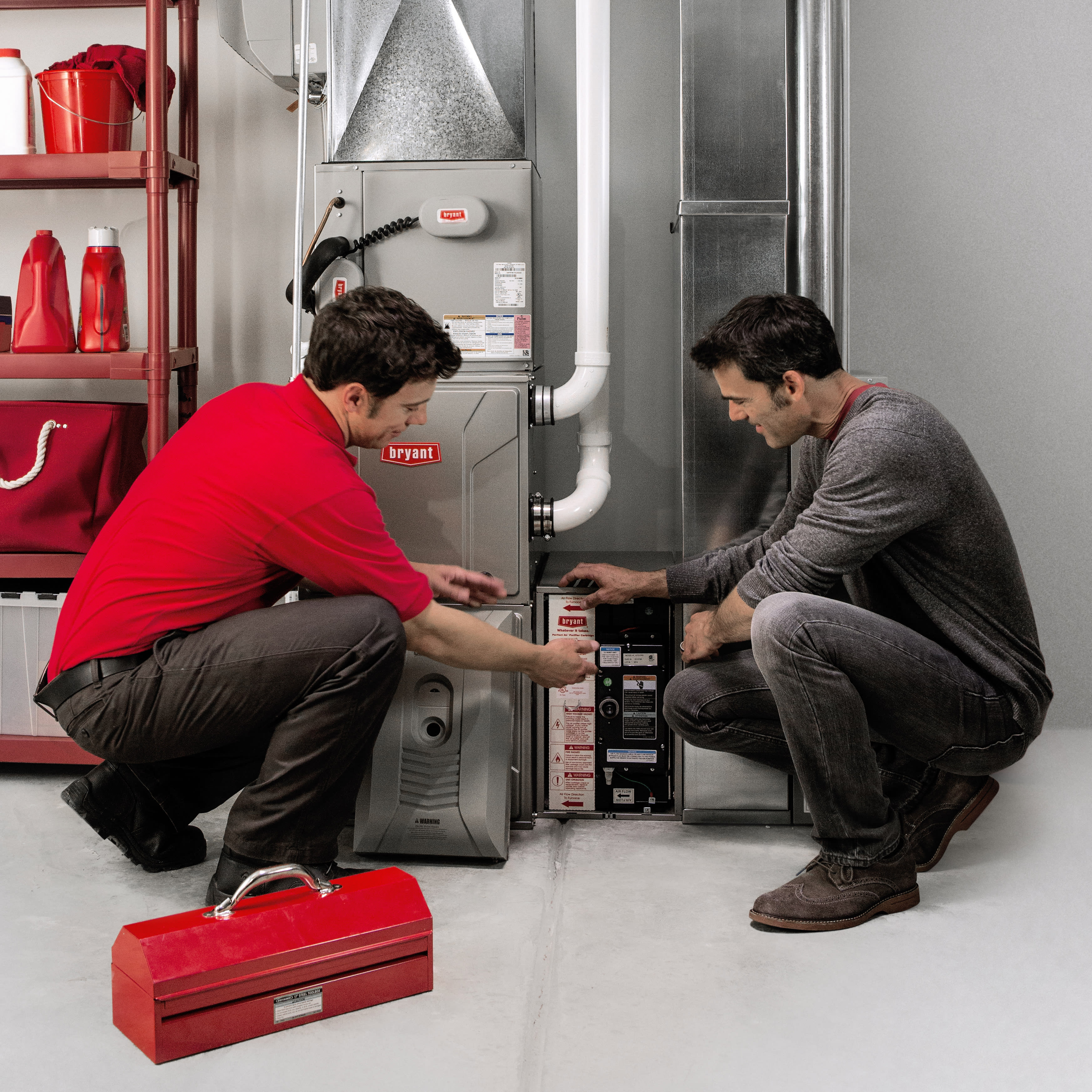 a bryant contractor services a gas furnace with homeowner watching