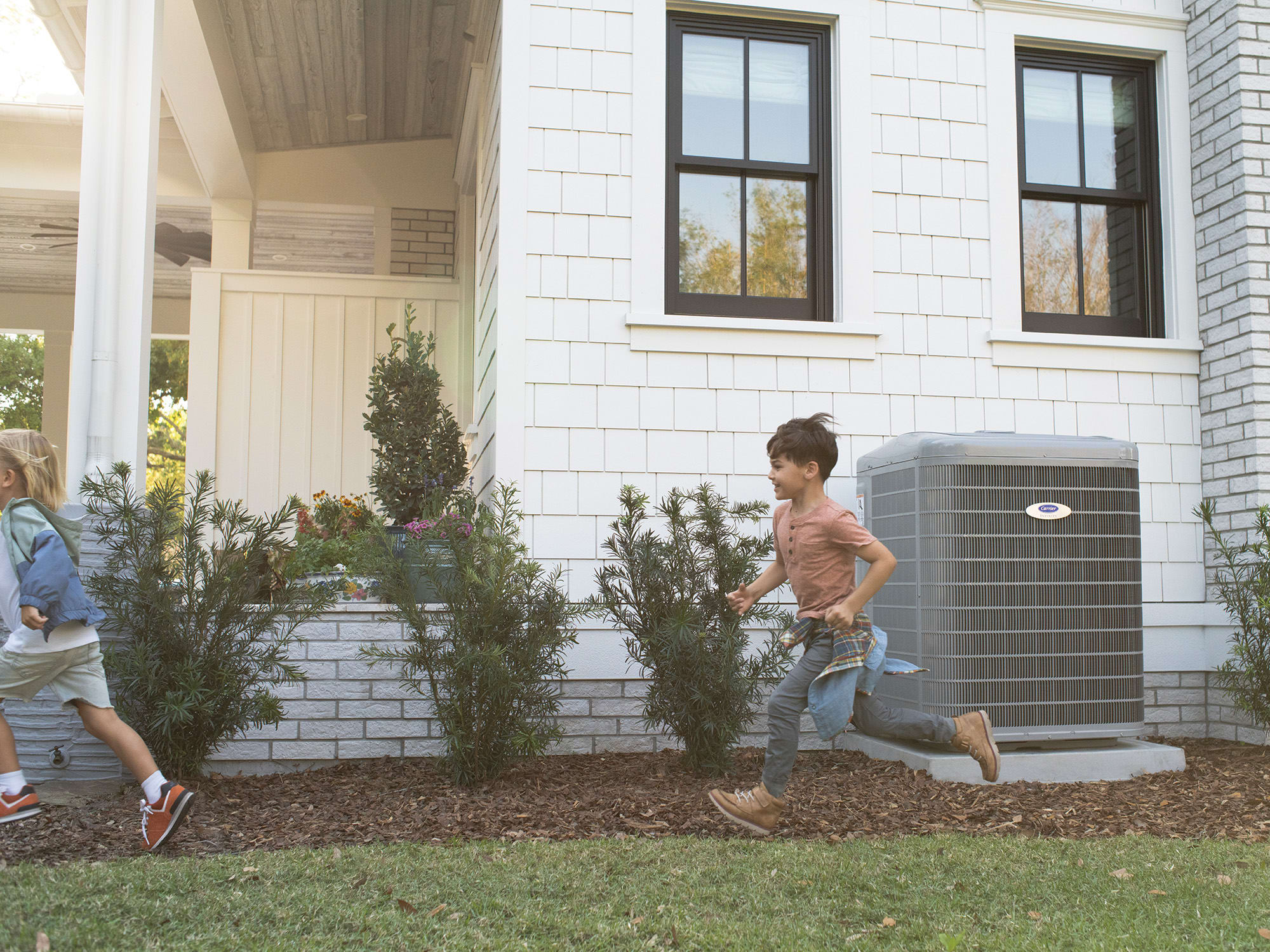 boys-running-by-carrier-heat-pump
