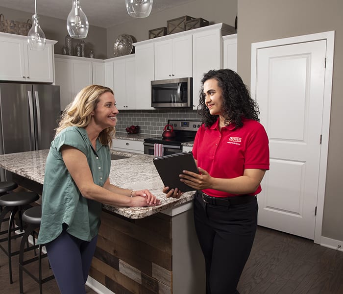 a bryant contractor talks to a female in the kitchen about how intelisense technology works