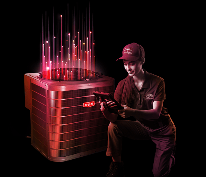 a bryant dealer kneels by a bryant heat pump with intelisense technology