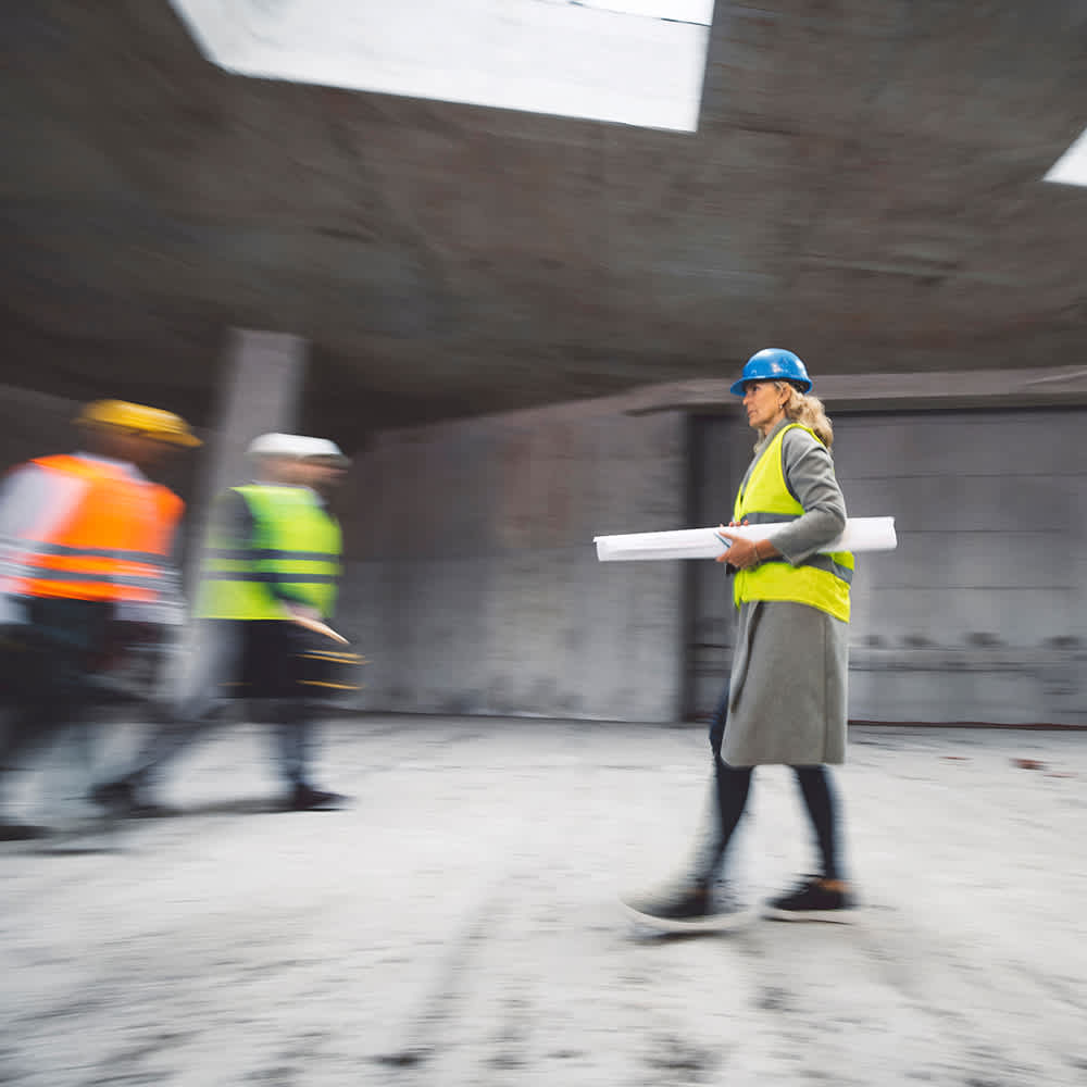 woman-with-hardhat-carrying-blueprints-1x1