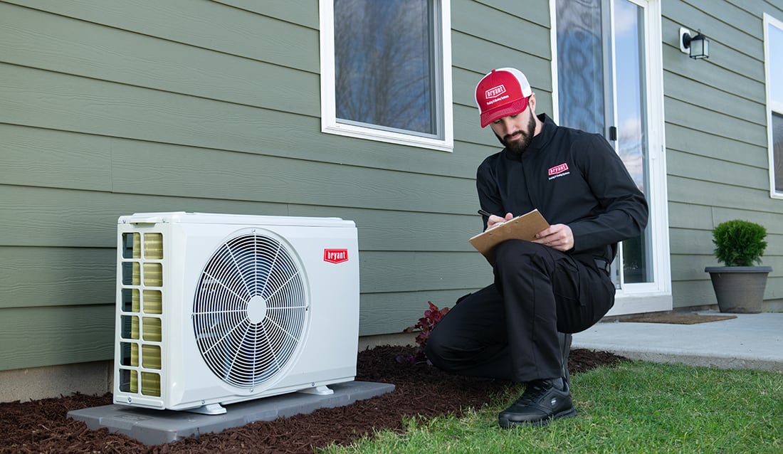 bryant_dealer_inspects_ductless_mini_split_unit_outside_home