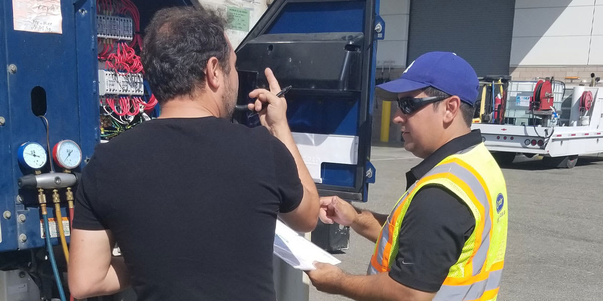 Carrier TechLINE Academy Training Schedule - instructor and technician standing next to refrigeration controls