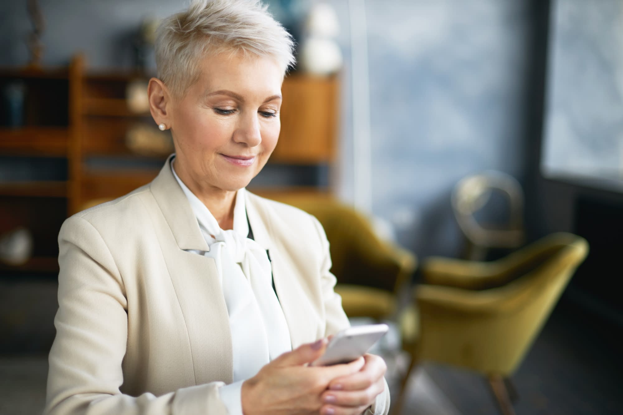 Close up of mature female real estate agent smiling while looking at mobile app