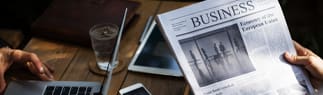 woman-with-business-newspaper-laptop-and-coffee-4x1