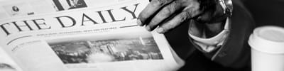 person-reading-newspaper-with-laptop-and-coffee-1x4