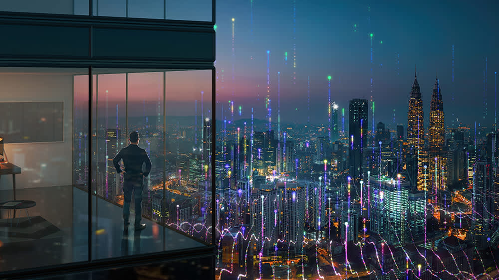 man-standing-in-office-looking-at-cityscape-16x9