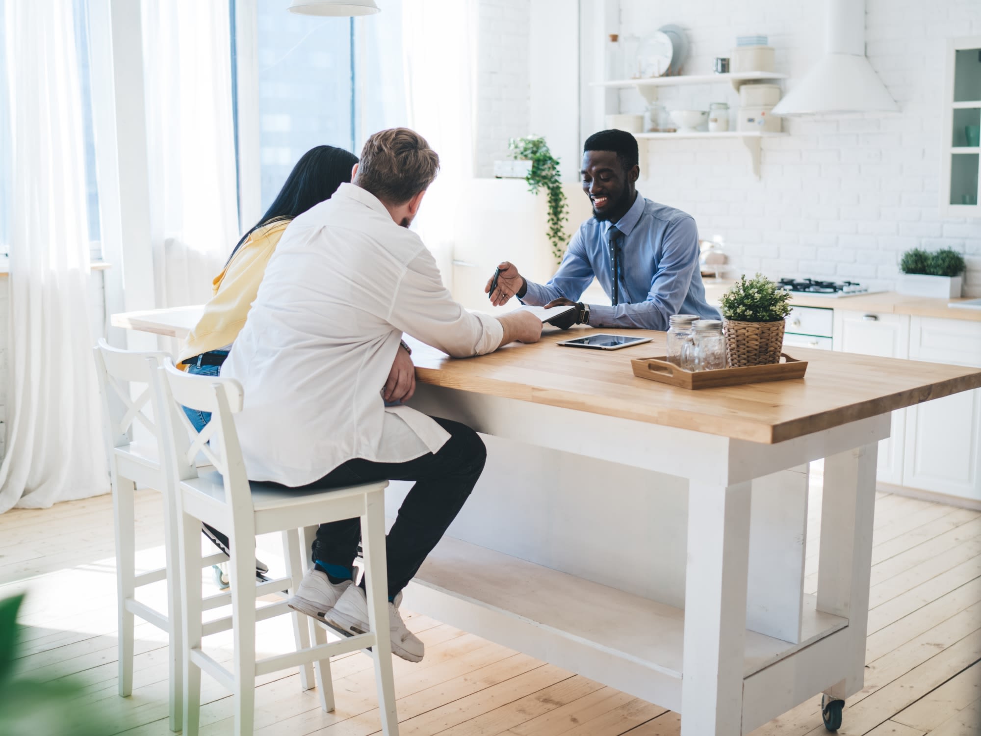 Agent sitting with couple at kitchen island reviewing home details