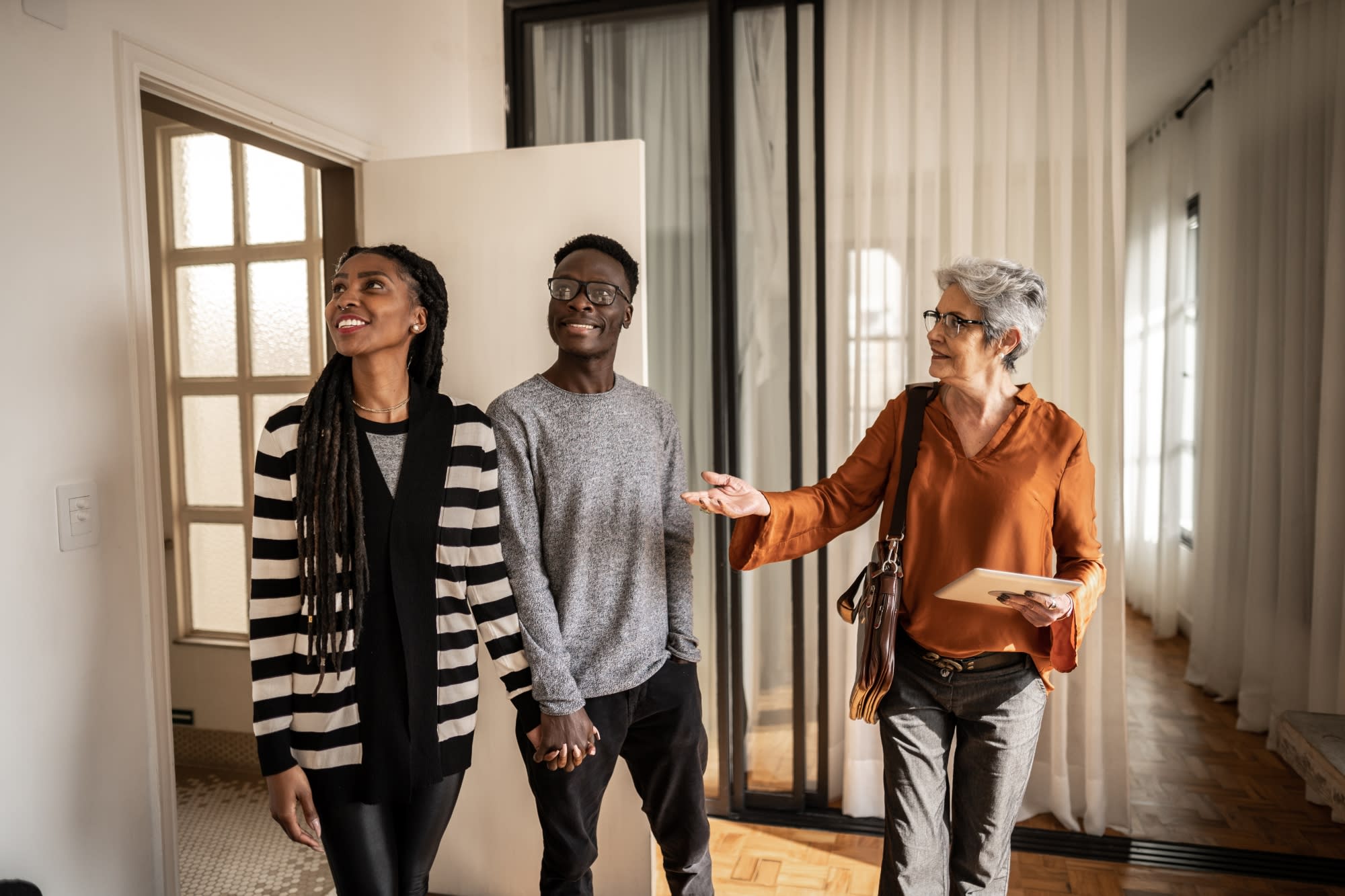 Mature real estate agent showing apartment to young couple