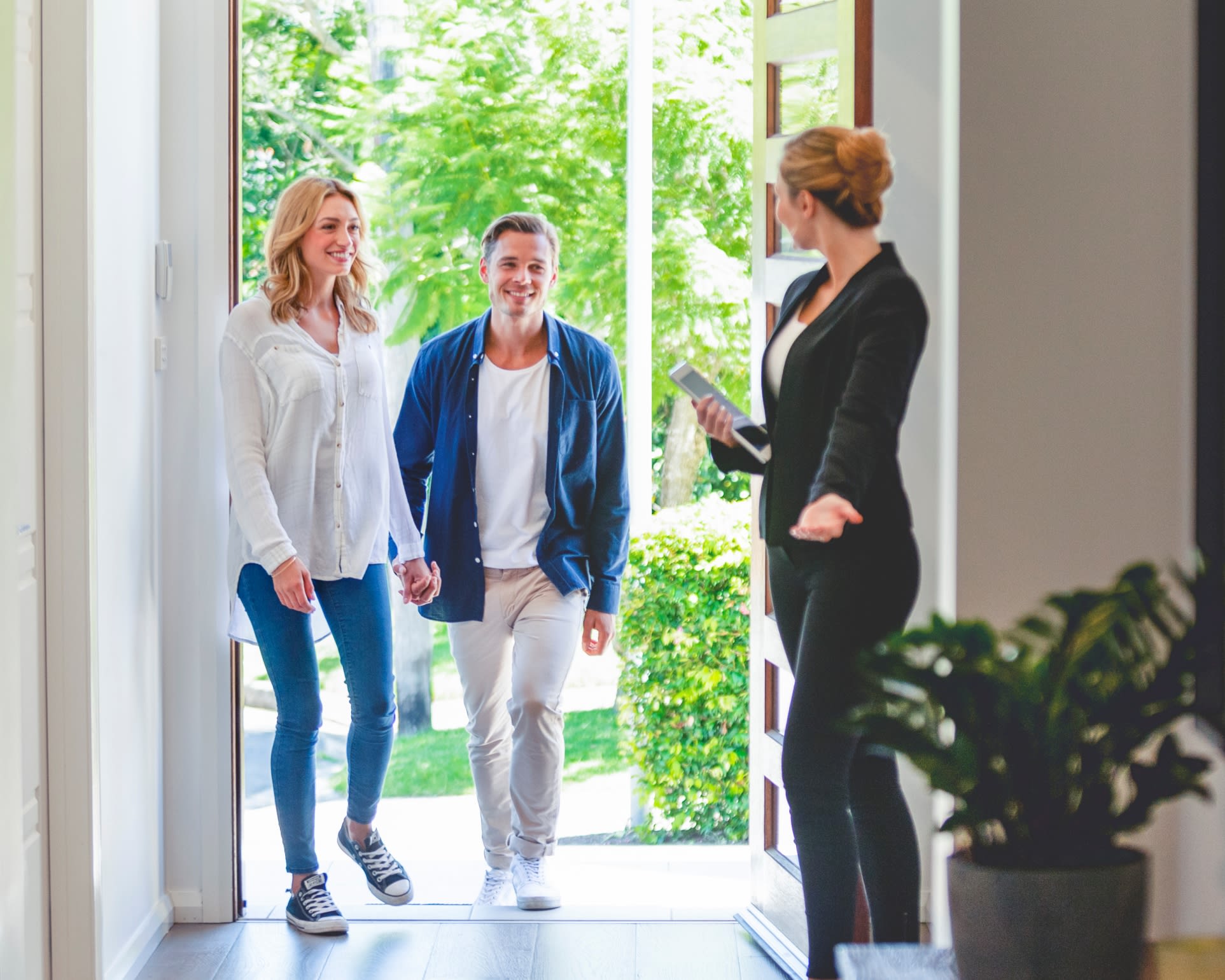 Real estate agent welcoming young couple into home for showing