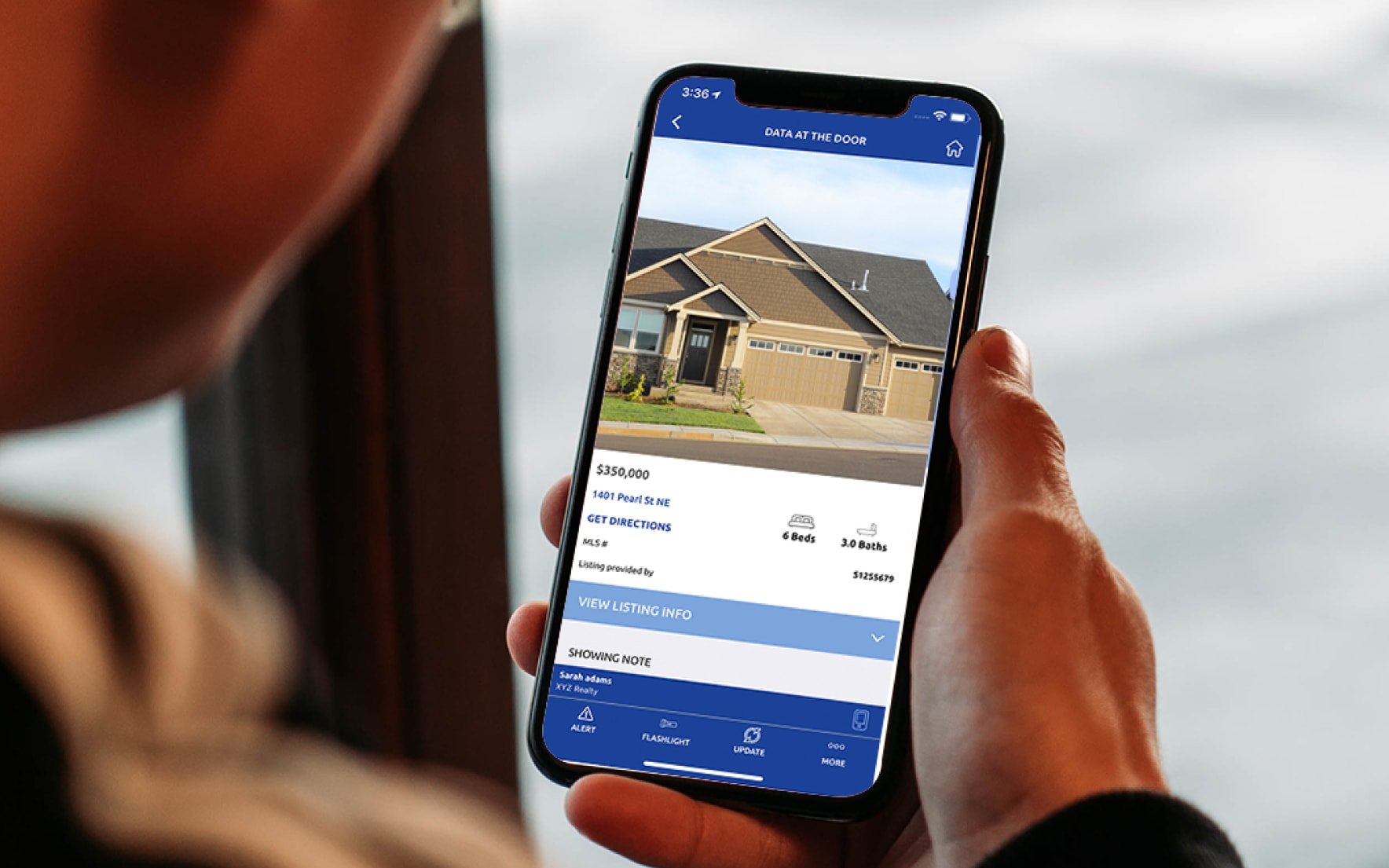 Real estate agent using Supra eKEY pro app to see home photo and price details.