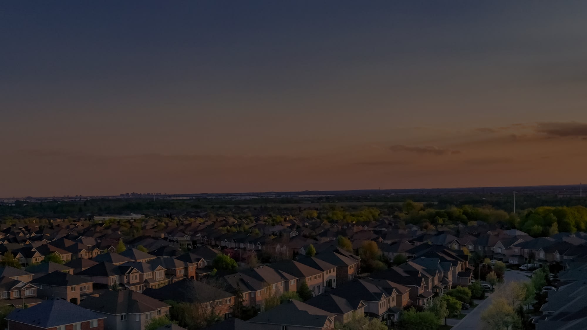 Aerial view of residential neighborhood with open sky and city skyline in the distance